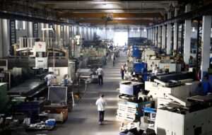 salle de production d'une industrie avec de la main d'œuvre humaine manipulant des machines-outils